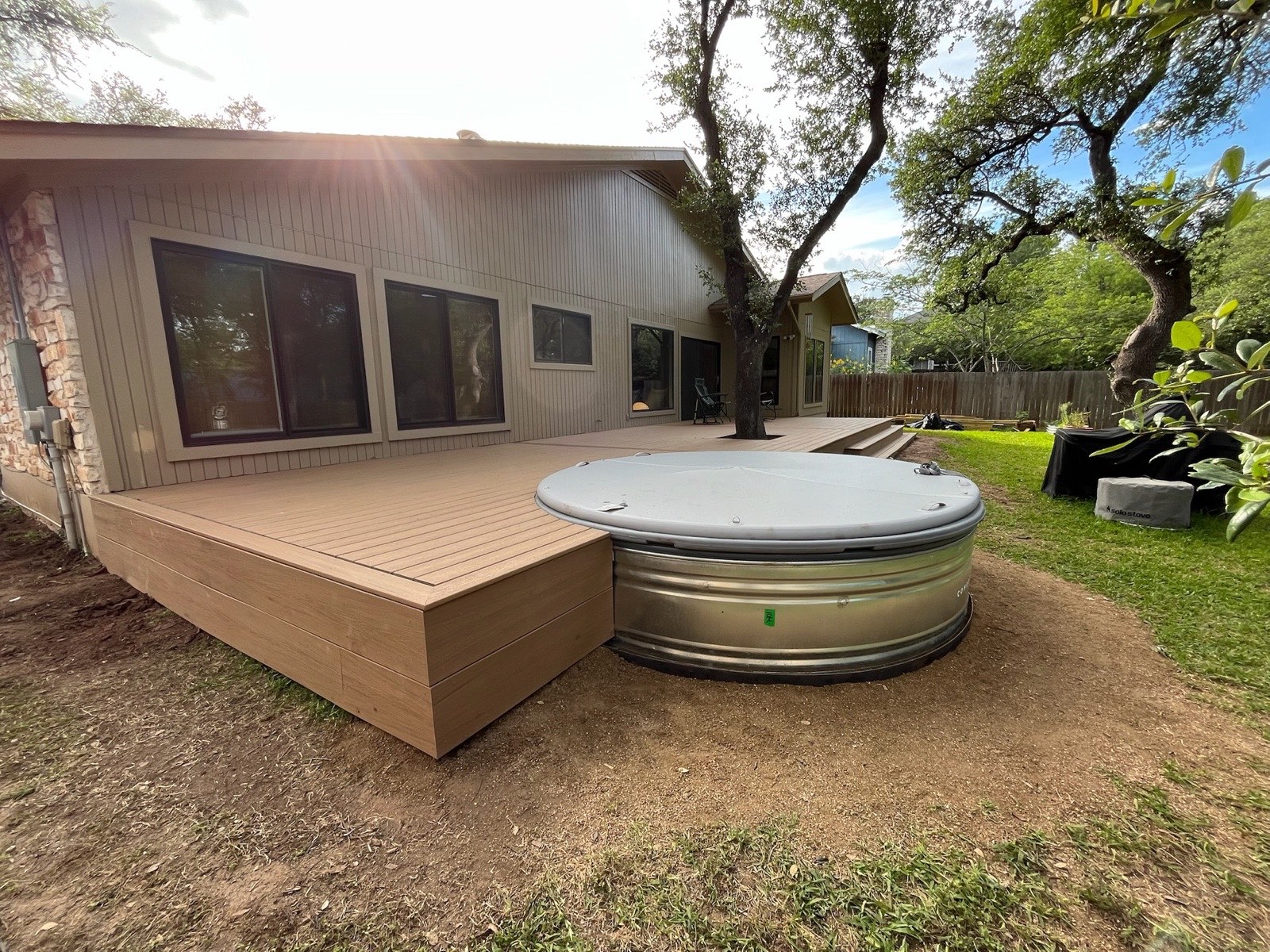 Wrap-around composite deck with a stock-tank cowboy pool built around an oak tree