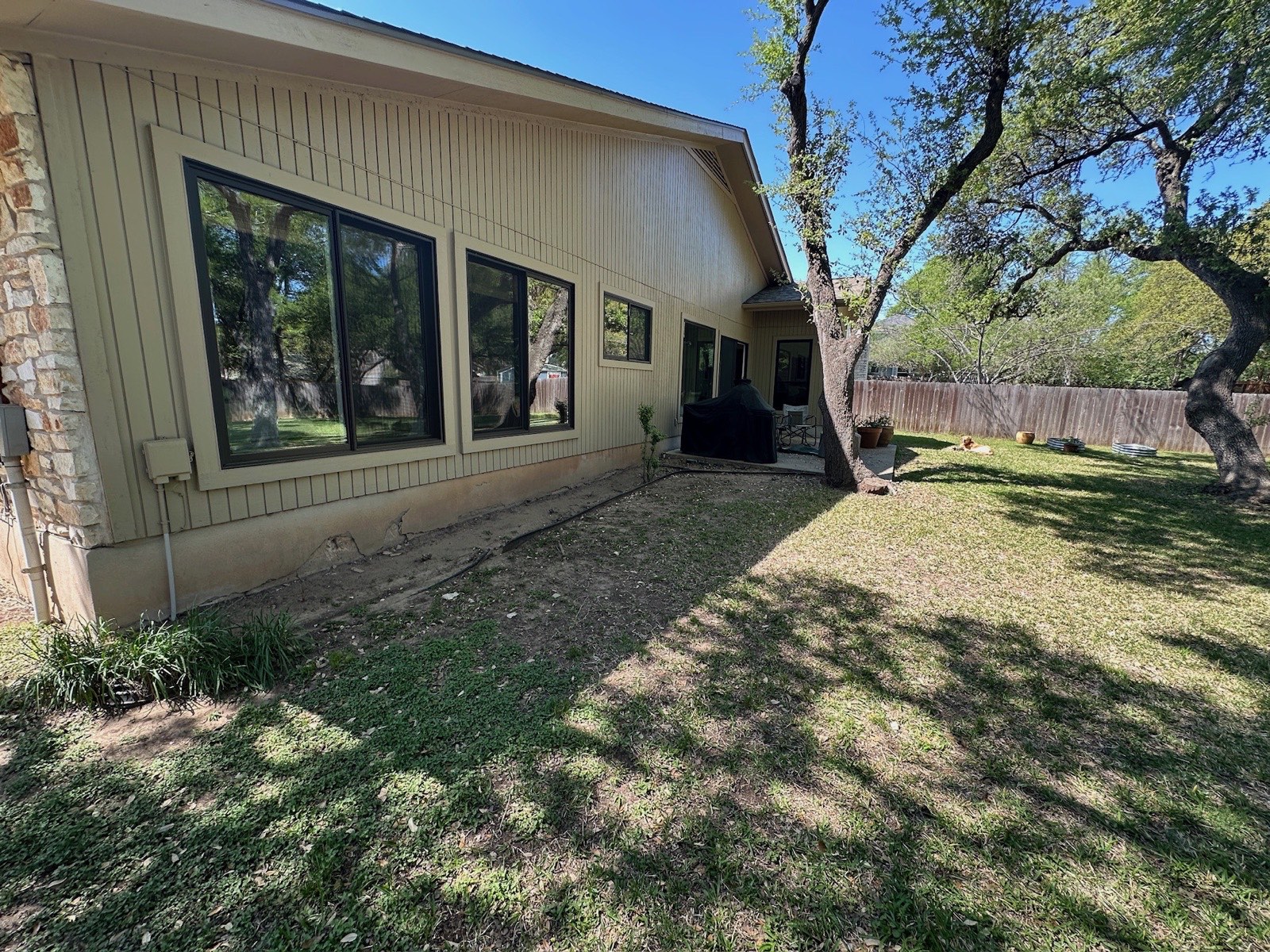 Bare dirt strip along the back of an Austin home before the deck build
