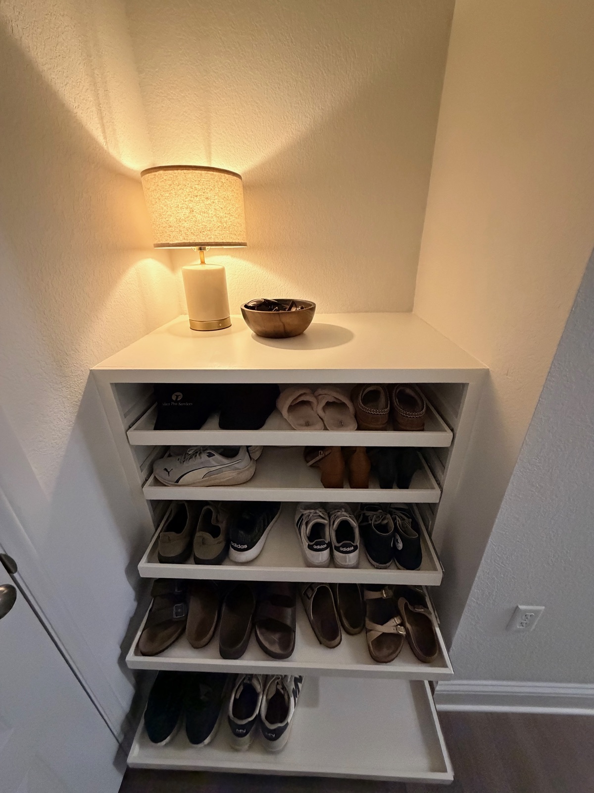 Custom built-in shoe cabinet with pull-out shelves and a styled top